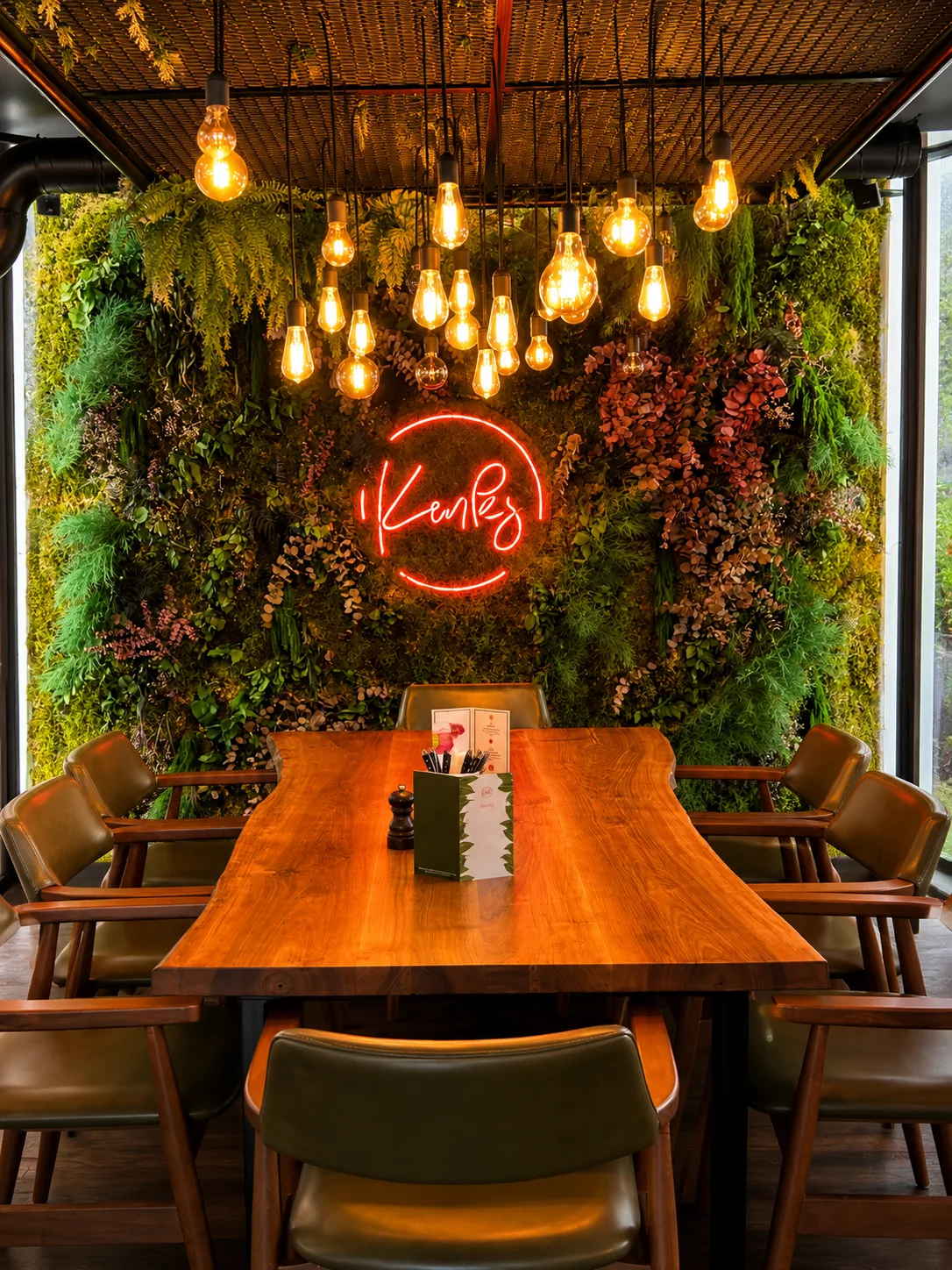 Kenks Restaurantbereich mit Pflanzenwand und Neon-Logo